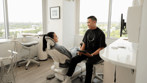 Dentist consulting with a smiling patient in a modern dental chair about veneers treatment
