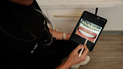 Dentist consulting with a smiling patient in a modern dental chair about veneers treatment